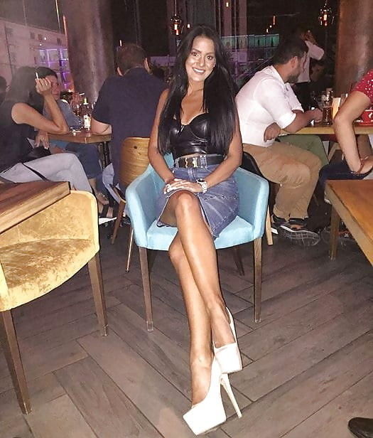 Tanned Leggy Brunete In Leather Top Denim Skirt And Shite Pumps